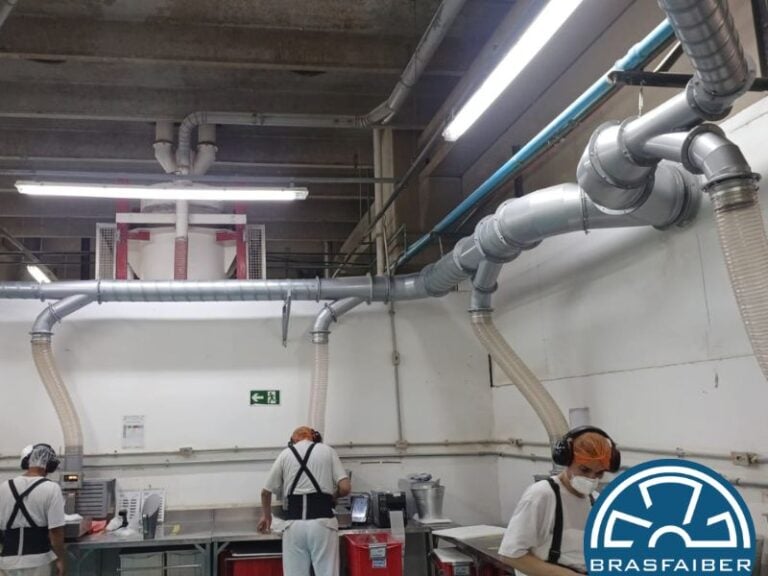 Captores de exaustão localizada instalados sobre os postos de trabalho, capturando o pó na própria fonte