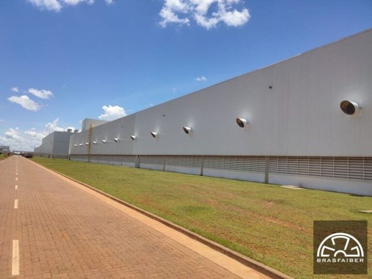 Galpão industrial de grande porte com exaustores e grelhas de ventilação ao longo da fachada