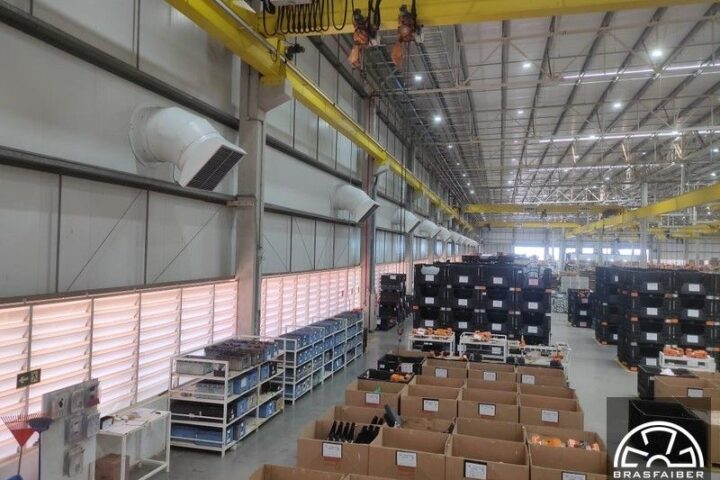 Vista interna do galpão com ventiladores de parede e grelhas