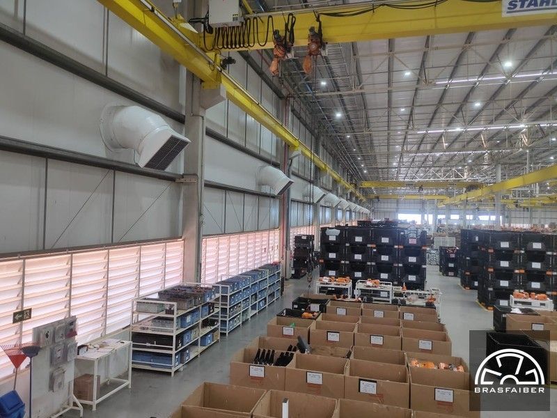 Vista interna do galpão com ventiladores de parede e grelhas