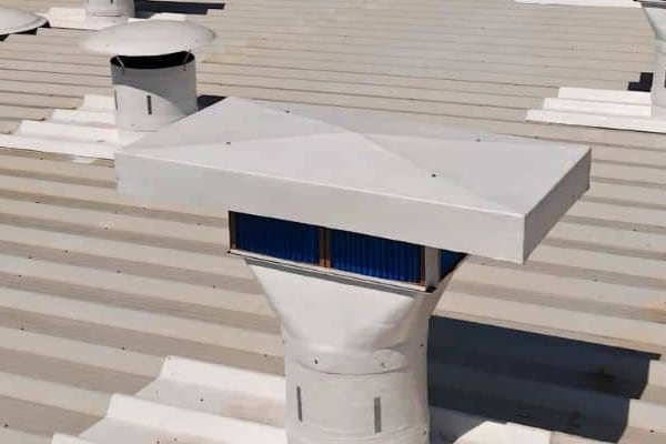 Insuflador de telhado com filtro visível na tomada de ar, instalado na cobertura de galpão industrial