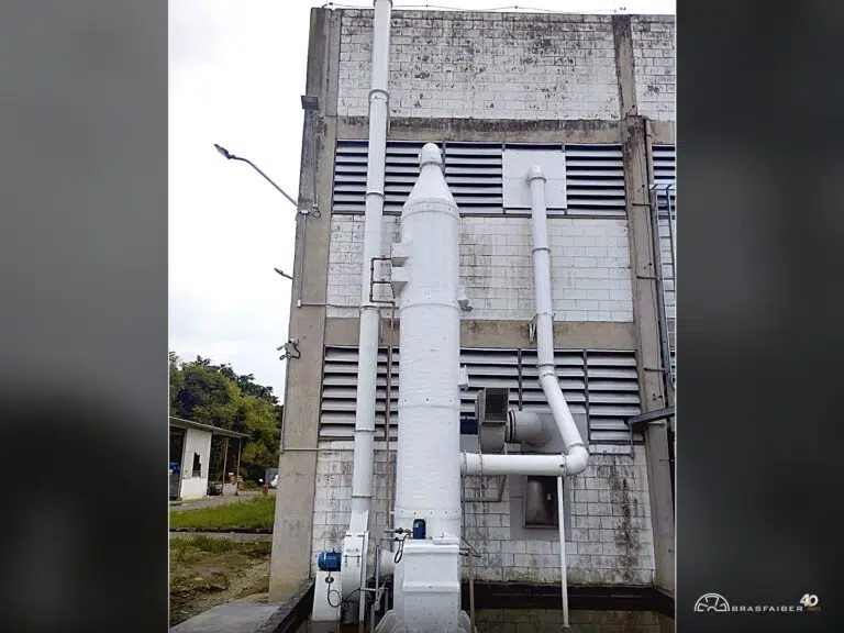 Torre lavadora de gases em PRFV vista por inteiro, do exaustor centrífugo na base ao topo cônico, com chaminé de descarga e duto de captação — Brasfaiber